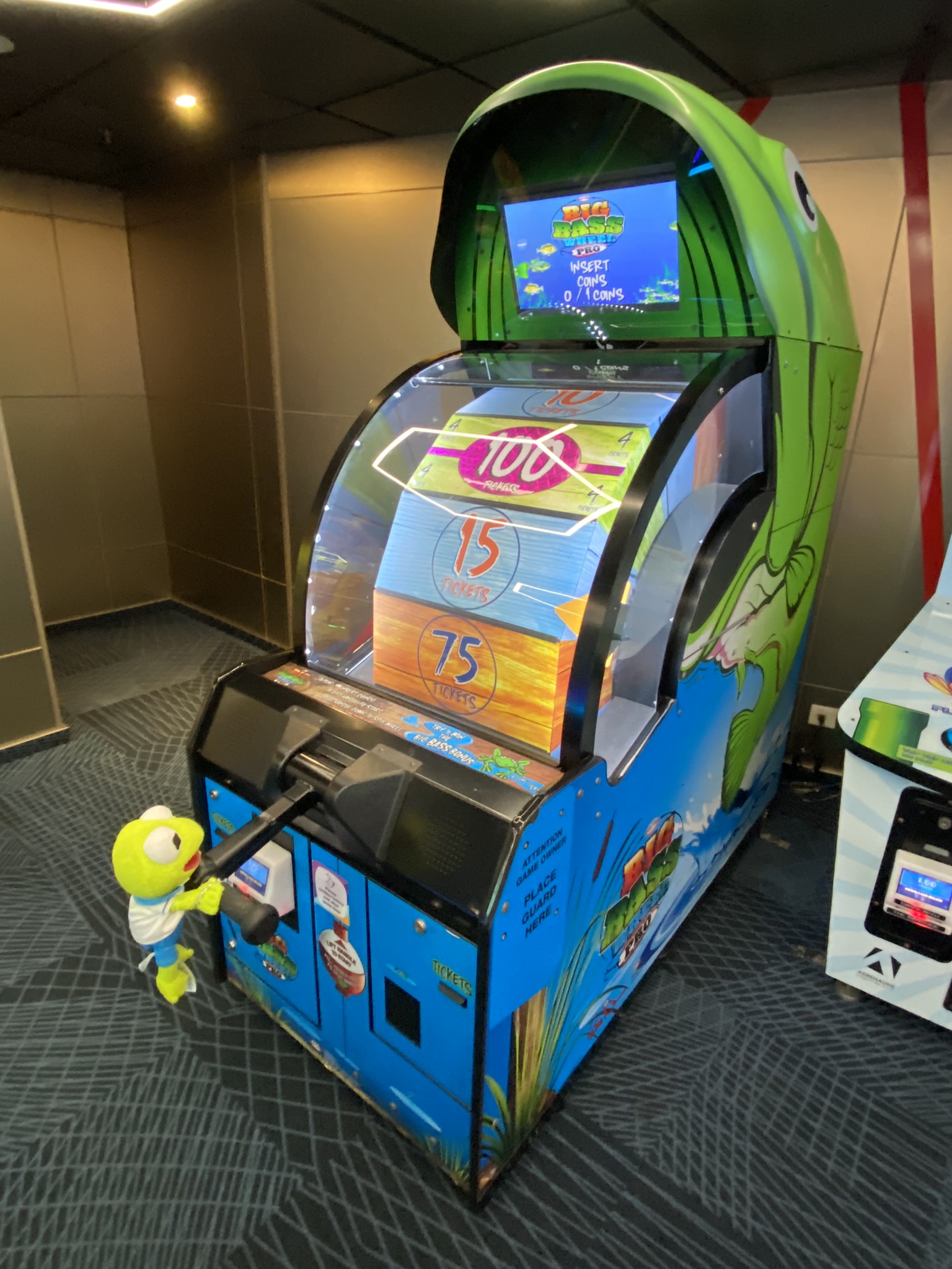 Kermit playing the Big Bass Wheel Pro game at the arcade.