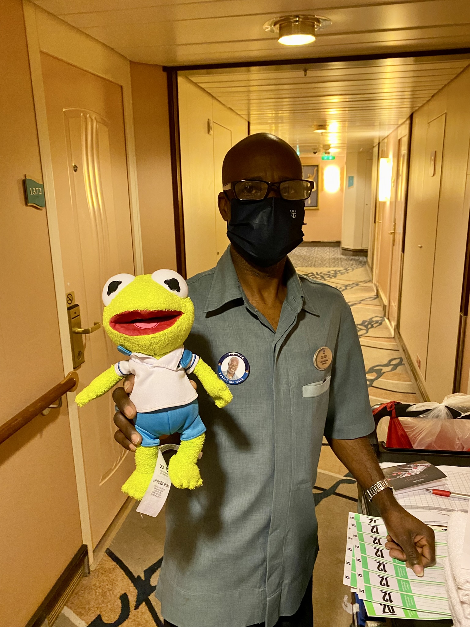 Kermit being held by a man from housekeeping in the stateroom hallway.